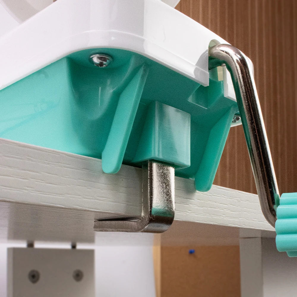 A close-up view of a white and teal hand crank yarn winder mechanism for knitting and crochet projects.