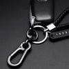 A close-up shot of a black personalized phone number keychain with a silver ring and braided leather rope.