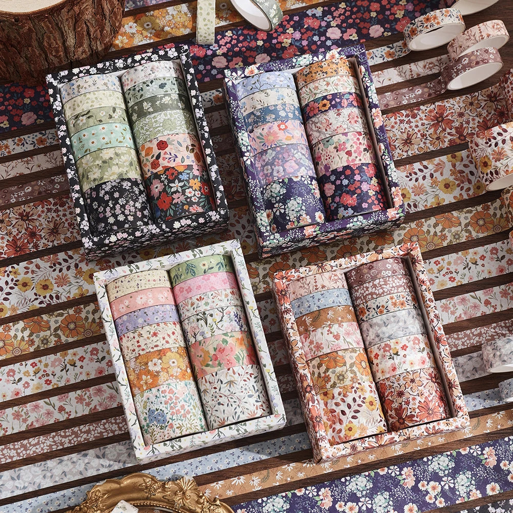 Collection de rouleaux de ruban washi floral vintage de différentes couleurs et motifs, exposés sur une surface en bois.