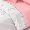 A close-up view of a white duvet cover with pink fabric and six round clips visible on the surface.