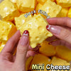 Hands are squeezing a yellow block filling mini cheese product.