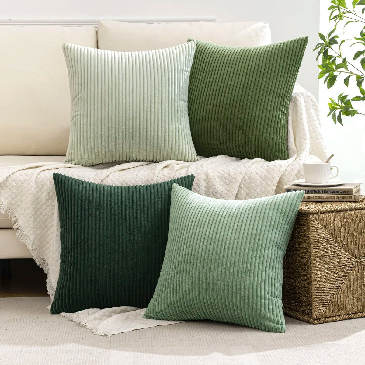 A collection of green and olive corduroy throw pillows displayed on a white sofa and woven basket.