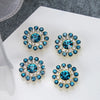 A set of five blue and clear rhinestones shaped like flowers on a white background.