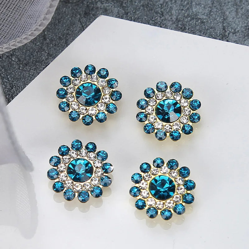 A set of five blue and clear rhinestones shaped like flowers on a white background.