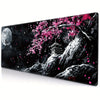 Un tapis de souris en acrylique noir avec la silhouette d'un arbre, des fleurs de cerisier roses et une pleine lune.