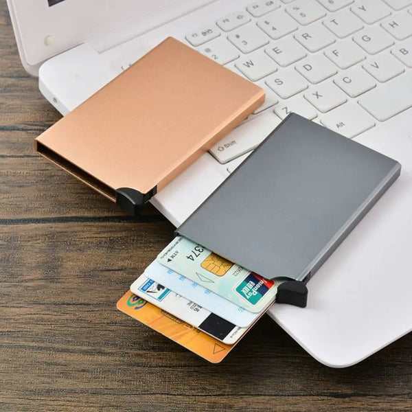 حامل بطاقات ألمنيوم محمول لحجب تقنية RFID موضوع على لوحة مفاتيح حاسوب محمول مع بطاقات ائتمان.