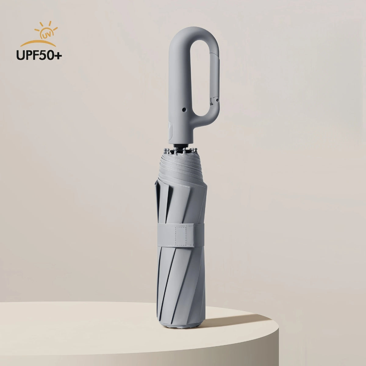A silver fully automatic windproof folding umbrella standing upright on a light surface.
