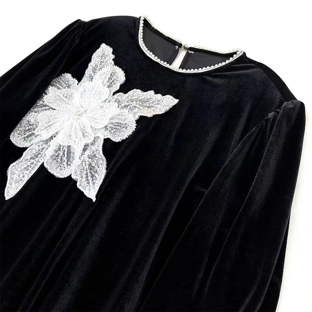 Black velvet fabric featuring a white floral lace applique patch on the shoulder