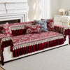 A deep red patterned sofa cover with quilted protection and decorative trim displayed on a white sofa.