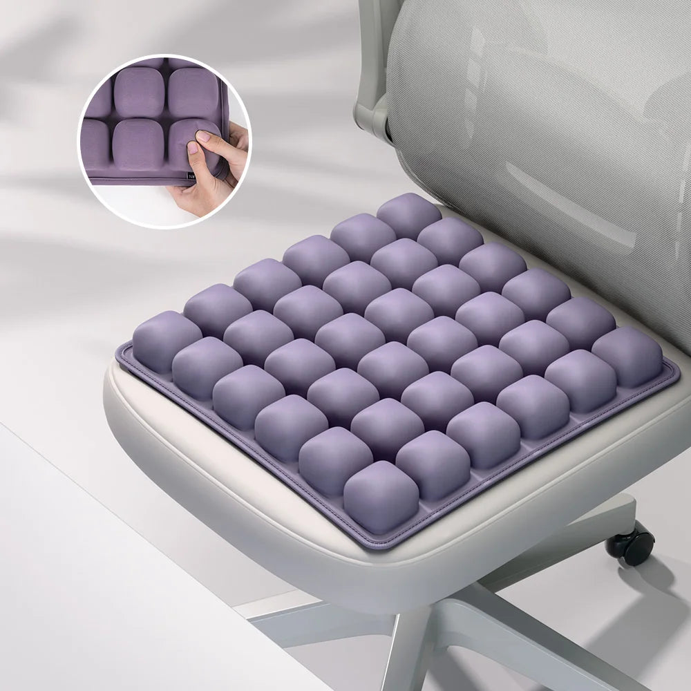 A purple press-to-inflate seat cushion is shown in a box and laid out on a light gray office chair.