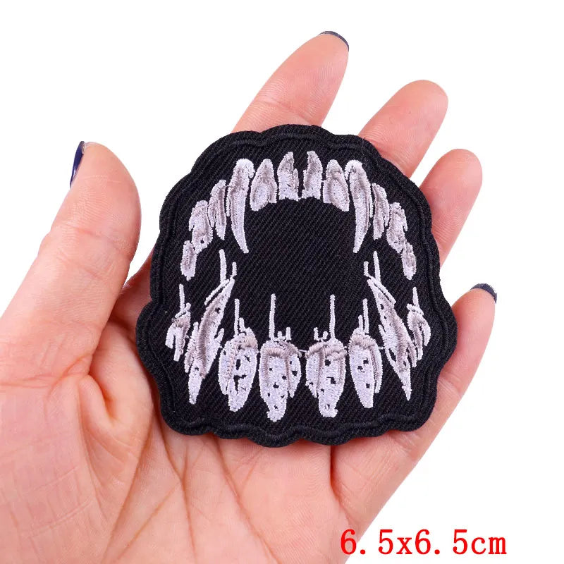 Black embroidered rose skull patch with iron-on backing shown in a hand.