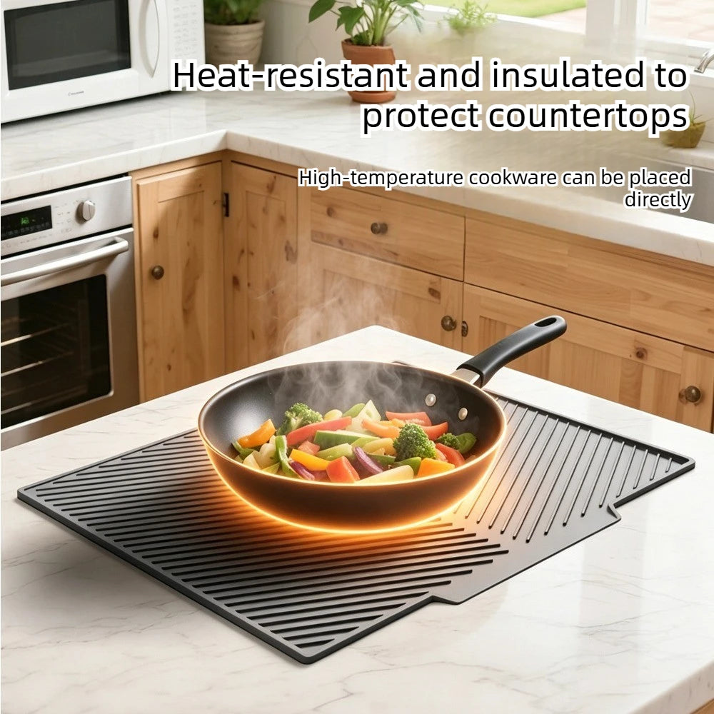 A black silicone dish drying mat is placed on a white countertop, protecting the surface from hot cookware.