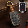 A black leather key fob case with a brass ring attached, next to a white electronic device.