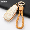 A gold-toned silicone car key fob cover attached to a braided leather cord, resting on a black surface.