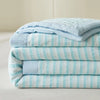 A stack of light blue and white striped breathable summer quilts with jacquard cotton covers.