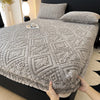 A gray warm plush mattress cover with an elastic edge is shown on a bed.