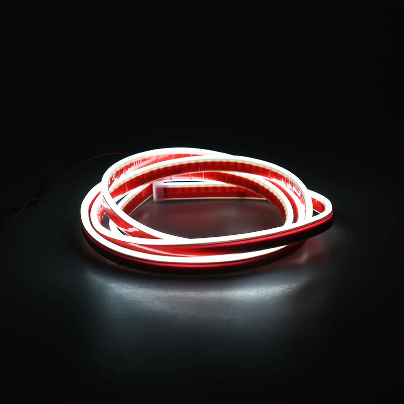 A flexible red and white LED strip light coiled in a circular shape against a dark background.