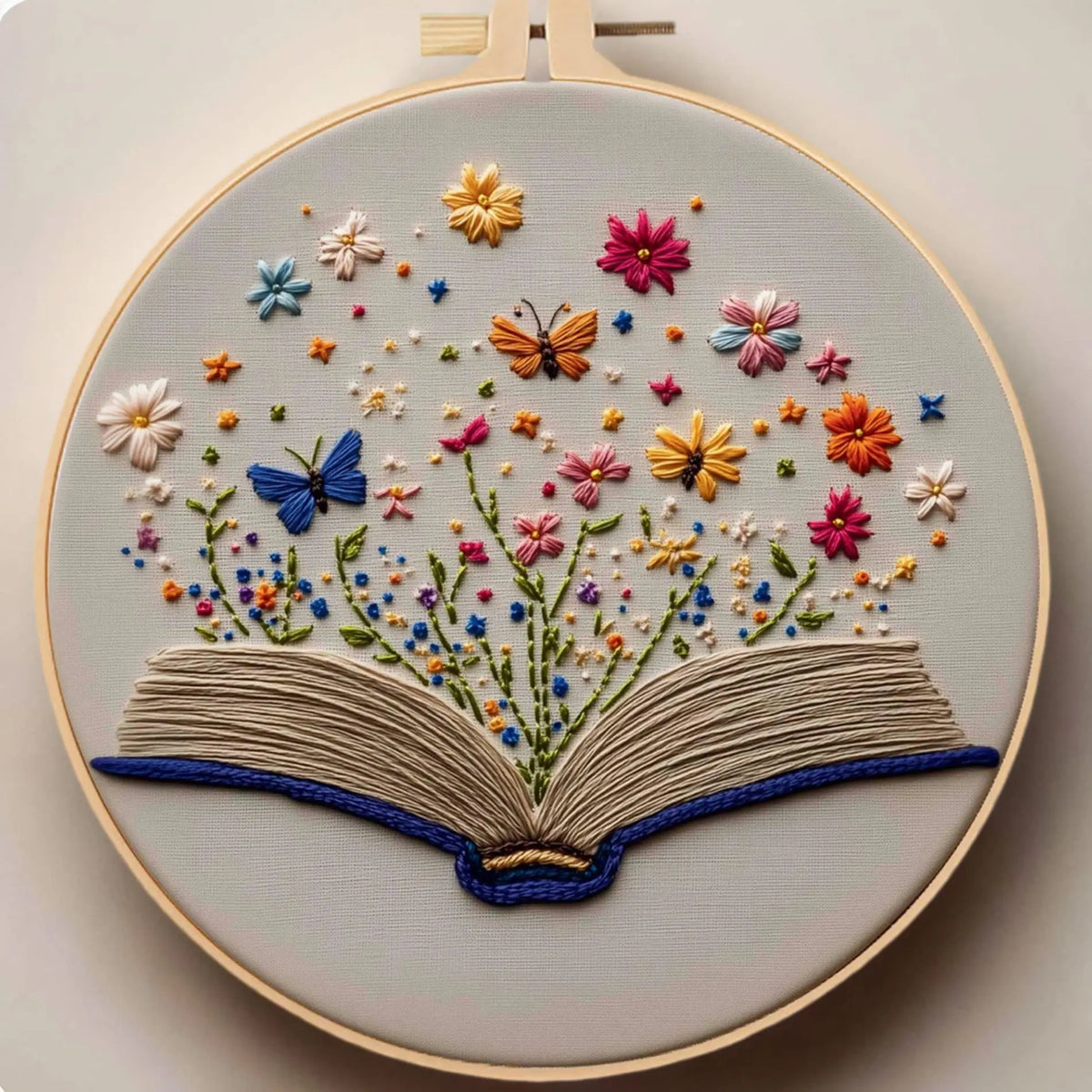A circular embroidery piece featuring floral designs and an open book made of thread.