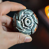 A hand holds a metallic, multi-faceted fidget spinner with intricate geometric patterns.