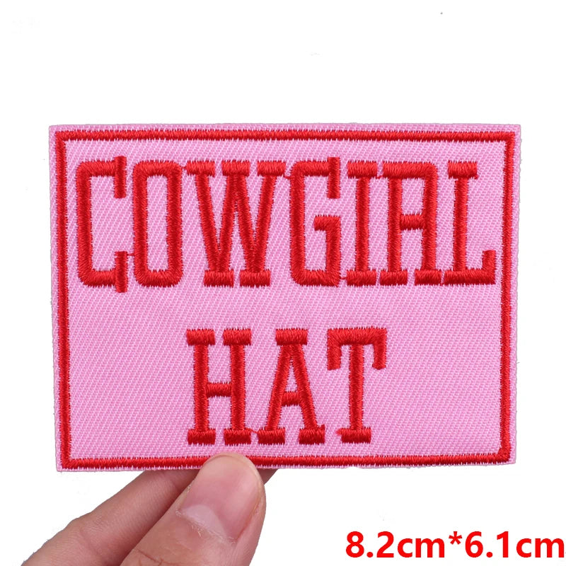 Pink embroidered patch with the text COWGIAL HAT in red thread
