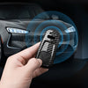 A hand holds a carbon fiber style key fob cover for an Audi car interior.