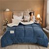 A deep blue weighted fleece blanket is displayed on a bed with a light gray duvet and neutral bedding.