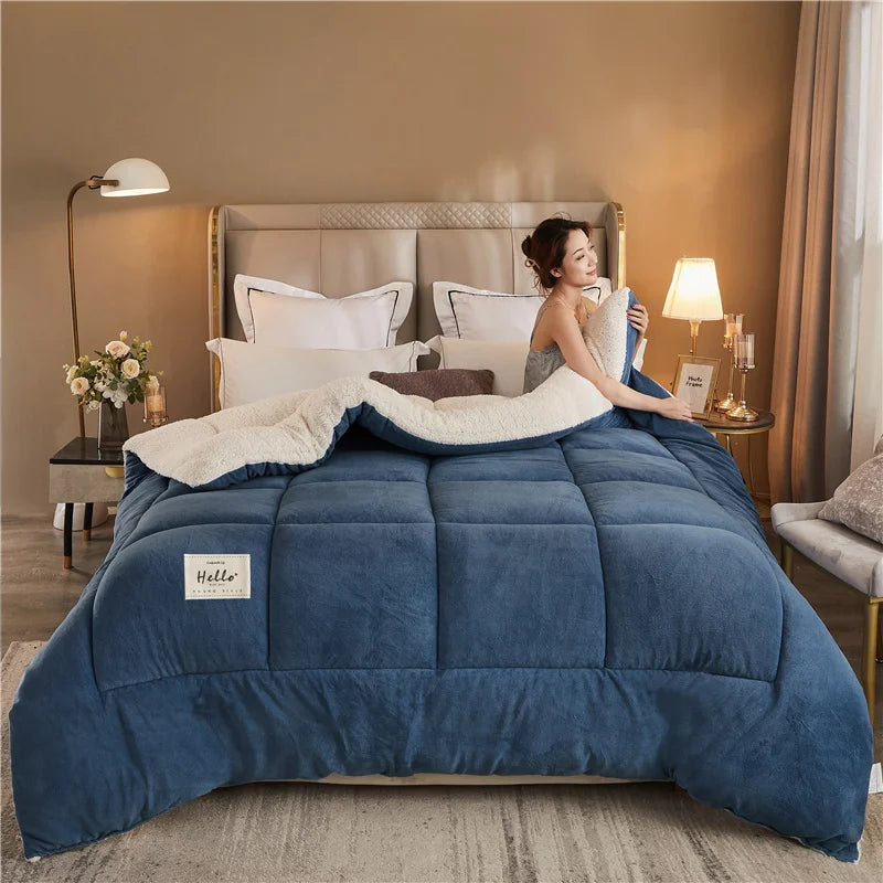 A deep blue weighted fleece blanket is displayed on a bed with a light gray duvet and neutral bedding.