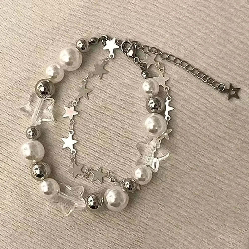 A double-layer bracelet featuring silver chains, clear crystals, and white pearls with small stars.