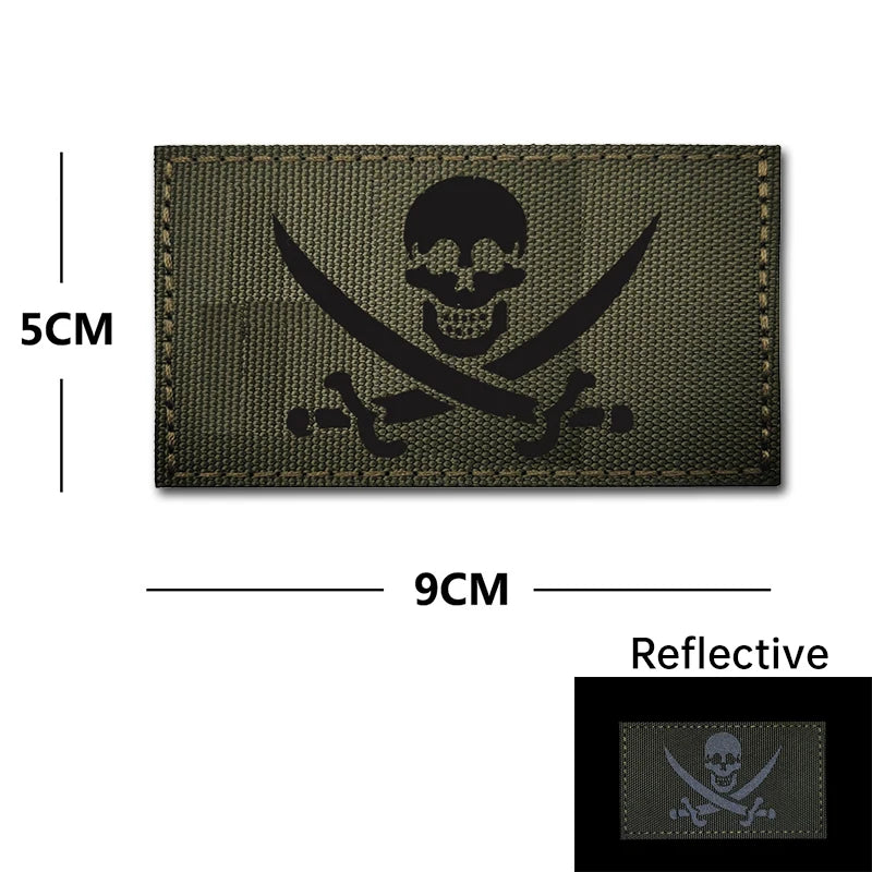Dark olive embroidered patch featuring a skull and crossed swords design with reflective accents