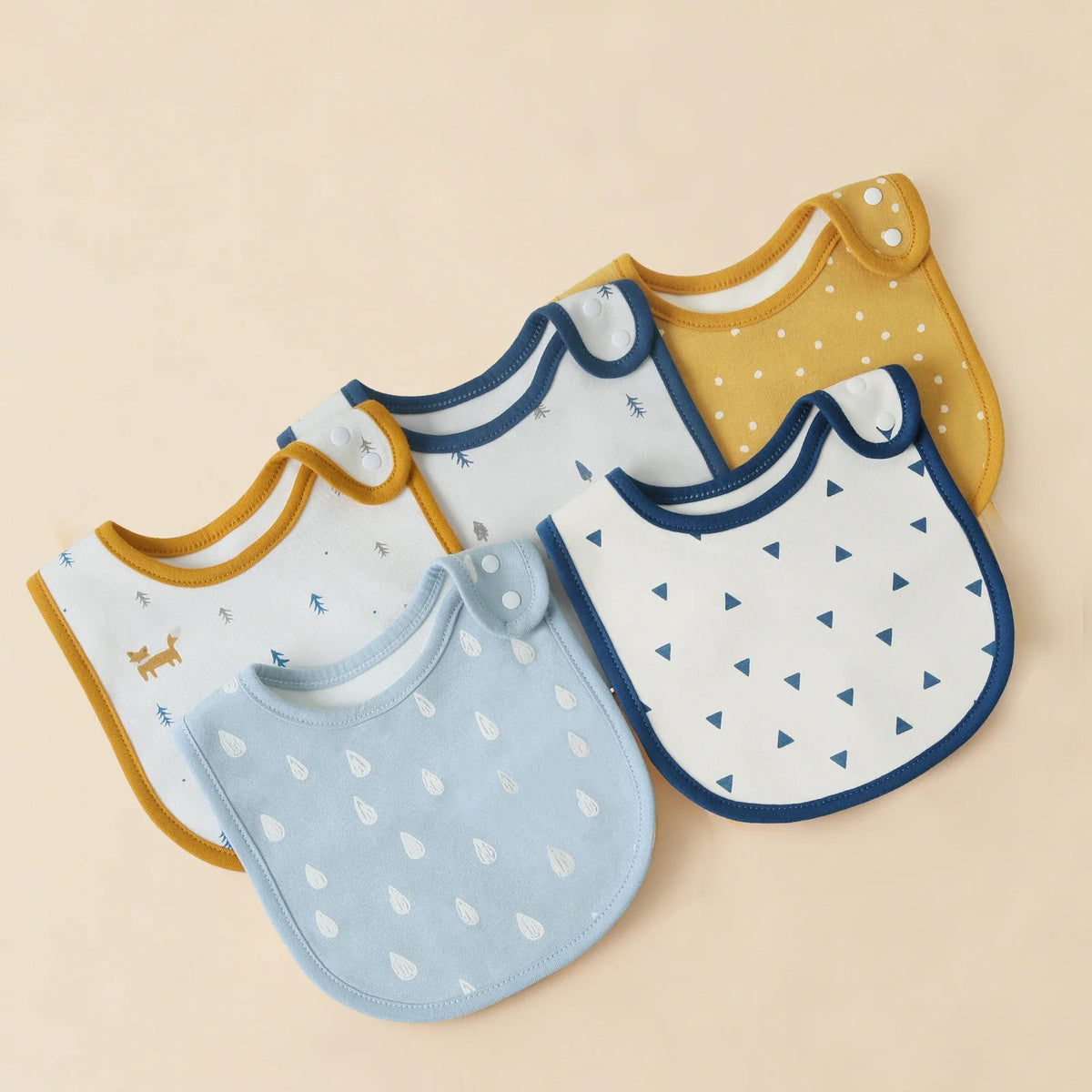 A collection of yellow and white cotton baby bibs with U-shaped designs arranged on a light background.