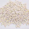 A pile of small white acrylic alphabet letter beads for jewelry making