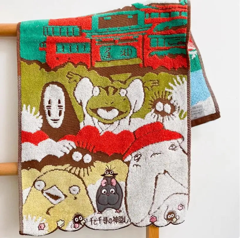 A hand-embroidered cartoon face towel featuring various animal and character faces in earthy tones.