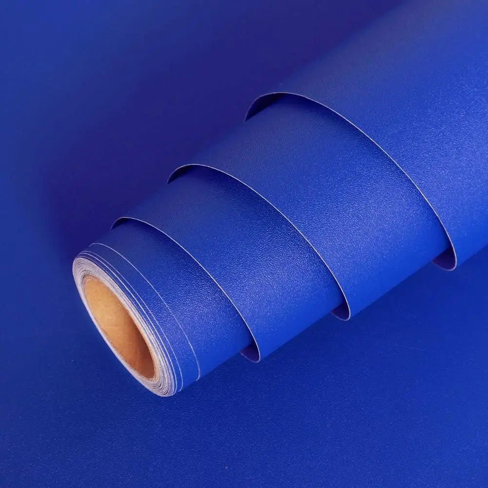 A roll of blue self-adhesive peel-and-stick wallpaper lying on a blue surface.