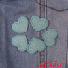 A set of five light blue glitter heart iron-on embroidered patches sewn onto a denim fabric.
