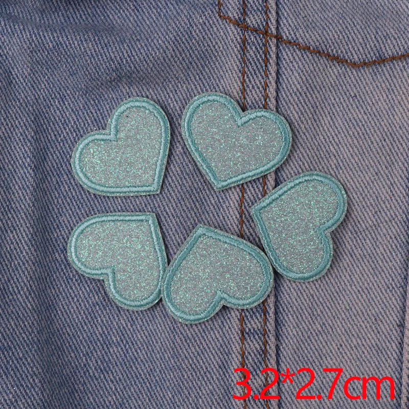 A set of five light blue glitter heart iron-on embroidered patches sewn onto a denim fabric.