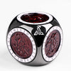 A black and silver metal spinner dice cube with red-tinted dice faces and a Celtic knot design.