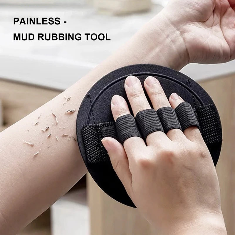 A hand is using a black mud rubbing tool on its wrist to exfoliate the skin.