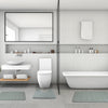 A modern bathroom featuring a white toilet, vanity, and bathtub with matching gray bath mats.