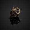 A bronze metal polyhedral die showing the number 3, resting on a reflective surface.