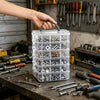 A hand holds a clear plastic storage organizer filled with various hardware and small parts on a workbench.