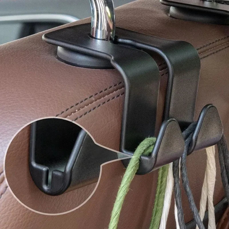 A close-up view of two black car headrest hooks attached to a brown leather handbag.