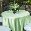 Elegant light green satin tablecloth draped on a round table with a floral centerpiece.