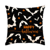 Almohada decorativa negra con patrón de murciélagos blancos y calabazas naranjas para Halloween.