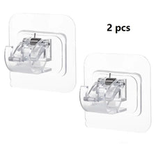 A set of two clear plastic no-drill adhesive curtain rod brackets for mounting curtains.