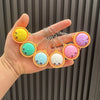 Eine Hand hält ein Set bunter dekorativer Knäppel-Anhänger in Pastellfarben.