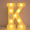 A glowing yellow LED letter K sign made of light bulbs used for home and party decor.