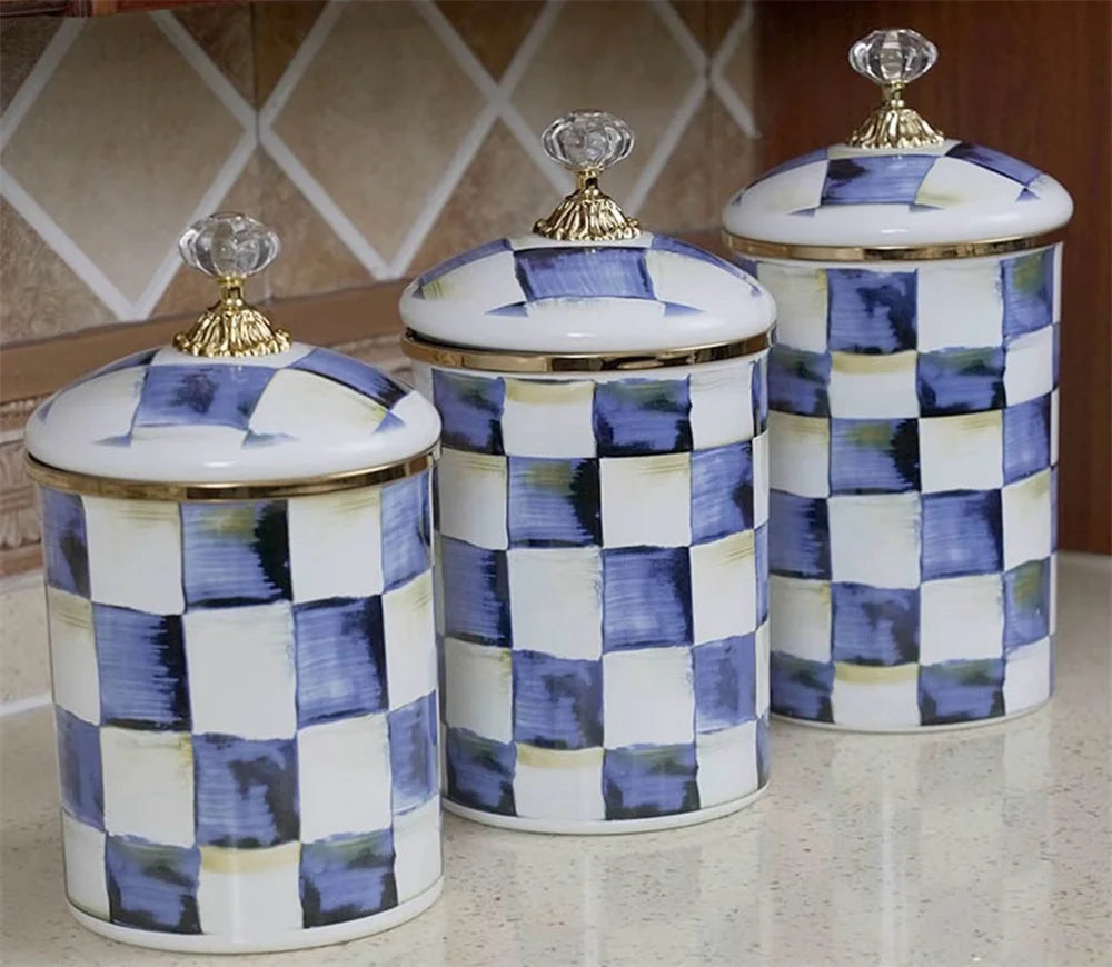 Three white porcelain storage jars with blue and yellow checkerboard patterns and gold lids
