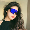 A woman wearing blue mirrored sunglasses with long dark hair against a light background.