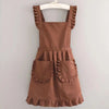 A brown Korean style cotton kitchen apron with adjustable neck straps and patch pockets displayed on a hanger.