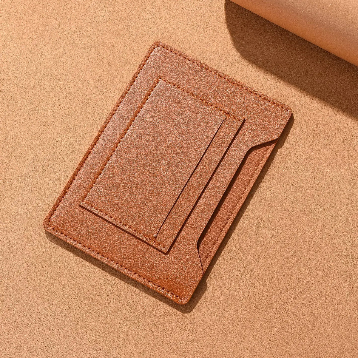 A tan leather passport holder with card slots lying on a beige background.
